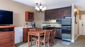 A compact kitchen with a dining table, chairs, a refrigerator, a microwave, and a coffee maker. - Ski-In 1BR | Spacious With Murphy Bed (West Dover)