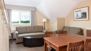 A cozy room with a sofa set, a wooden dining table, and a lamp. - Ski-In Mountain Suite | Cozy Escape (West Dover)