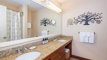 A bathroom with two sinks, a large mirror, and a tree-shaped wall decoration.