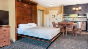 A compact hotel room with a bed, a desk, and a kitchenette. - Expansive 2BR | Sleeps 10 | Ski-In (West Dover)
