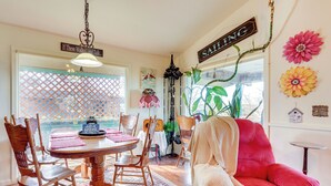 A dining area with a wooden table and chairs, a red sofa, and a hanging plant. - 'The Treehouse' in Cherokee Village: Deck & Views (Cherokee Village)