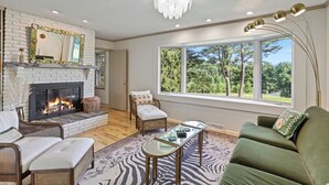 A living room with a fireplace, a large window, a sofa, and a coffee table.