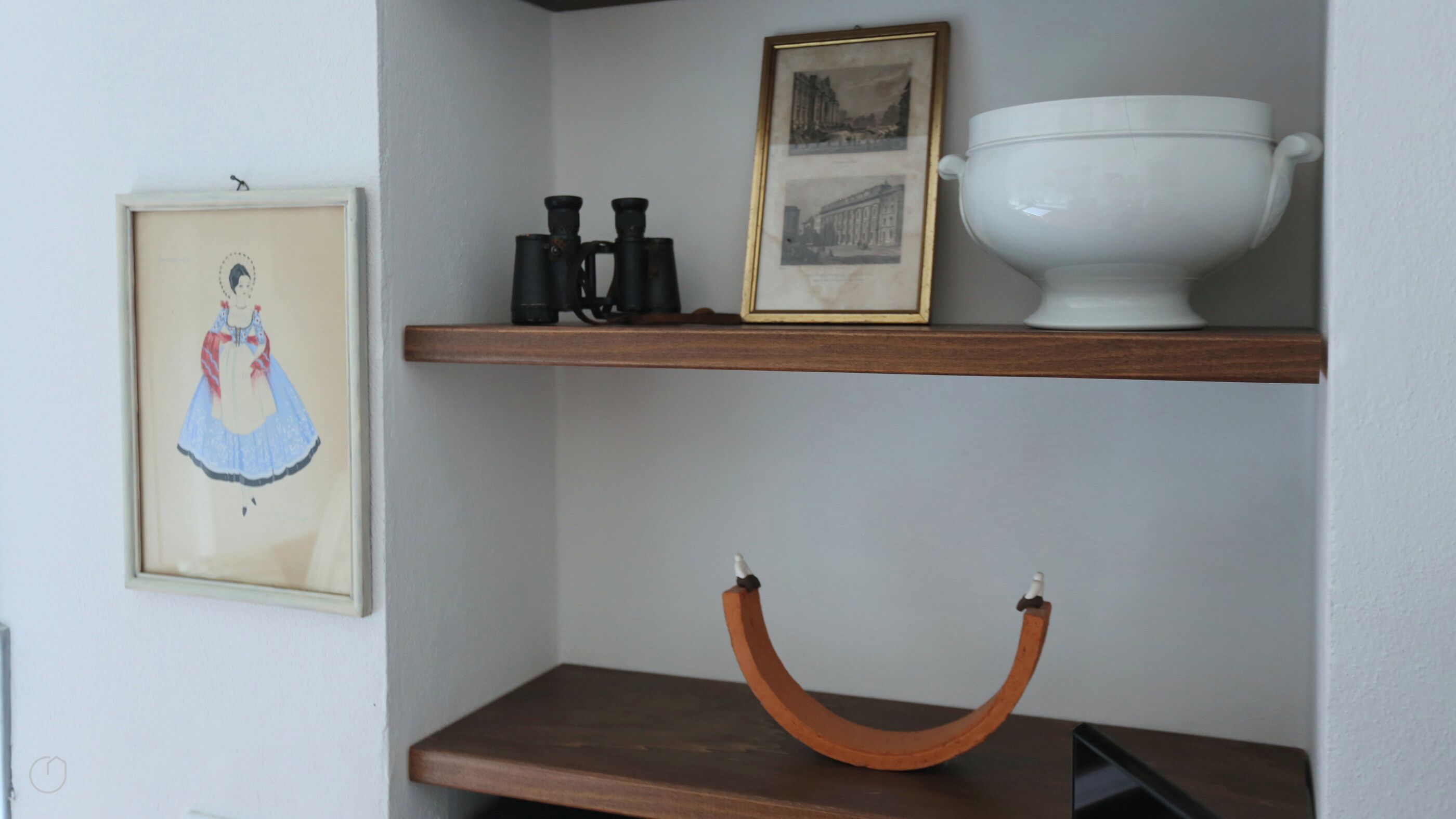 A shelf with a framed picture, a white bowl, and a curved object.