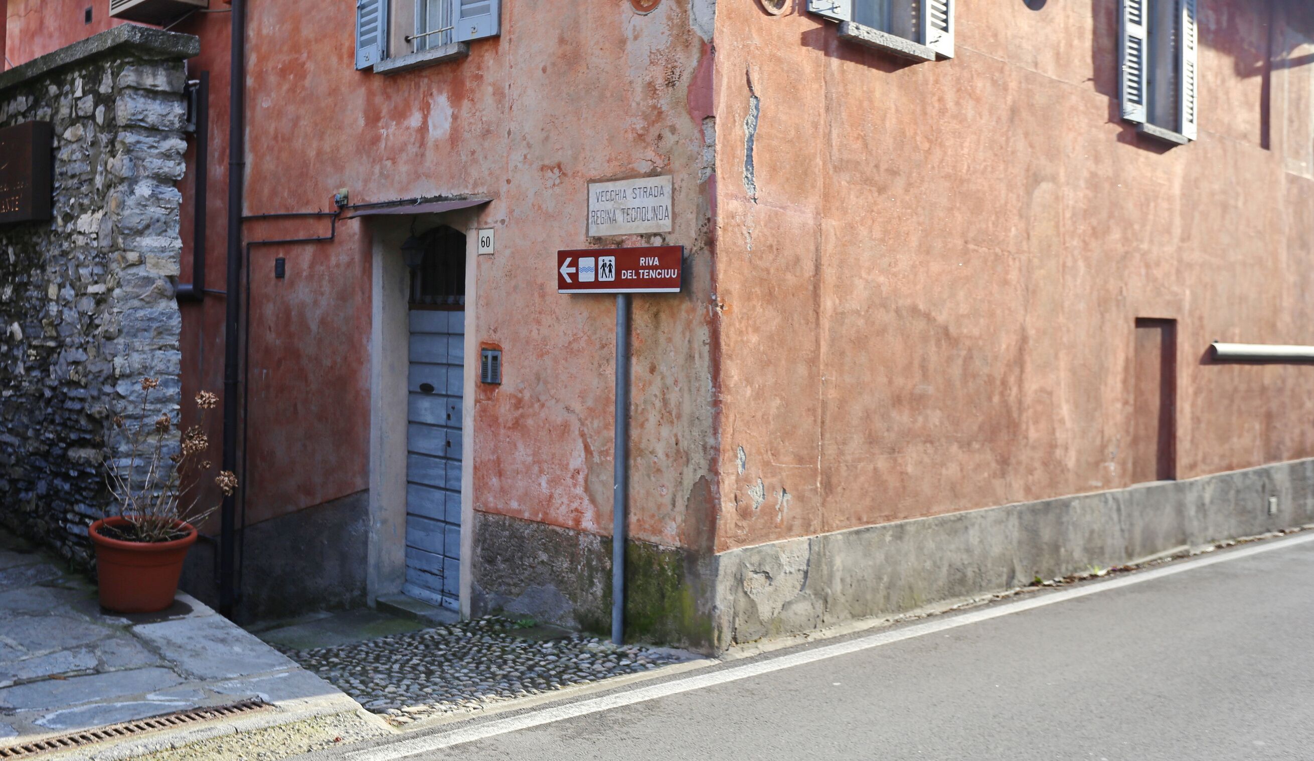 A building with a stone facade, a door, and a sign indicating a location.
