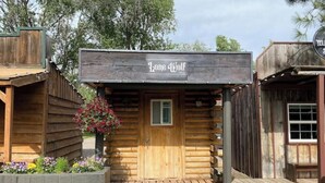 Eine rustikale Holzhütte mit dem Schild "Lone Wolf", einer Holztür und einem kleinen Fenster.