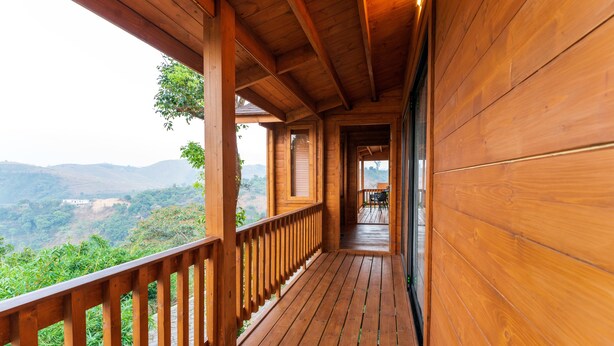 A wooden balcony with a view of a mountainous landscape. - Vaga Rowood by WanderEase (Vagamon)