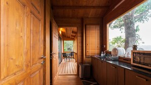 A wooden interior with a kitchen area, a dining table, and a view of the outdoors. - Vaga Rowood by WanderEase (Vagamon)