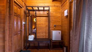 A wooden interior with a bench, a small refrigerator, and a trash bin. - Vaga Rowood by WanderEase (Vagamon)