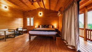 A wooden cabin bedroom with a bed, two bedside tables, a chair, and a window. - Vaga Rowood by WanderEase (Vagamon)
