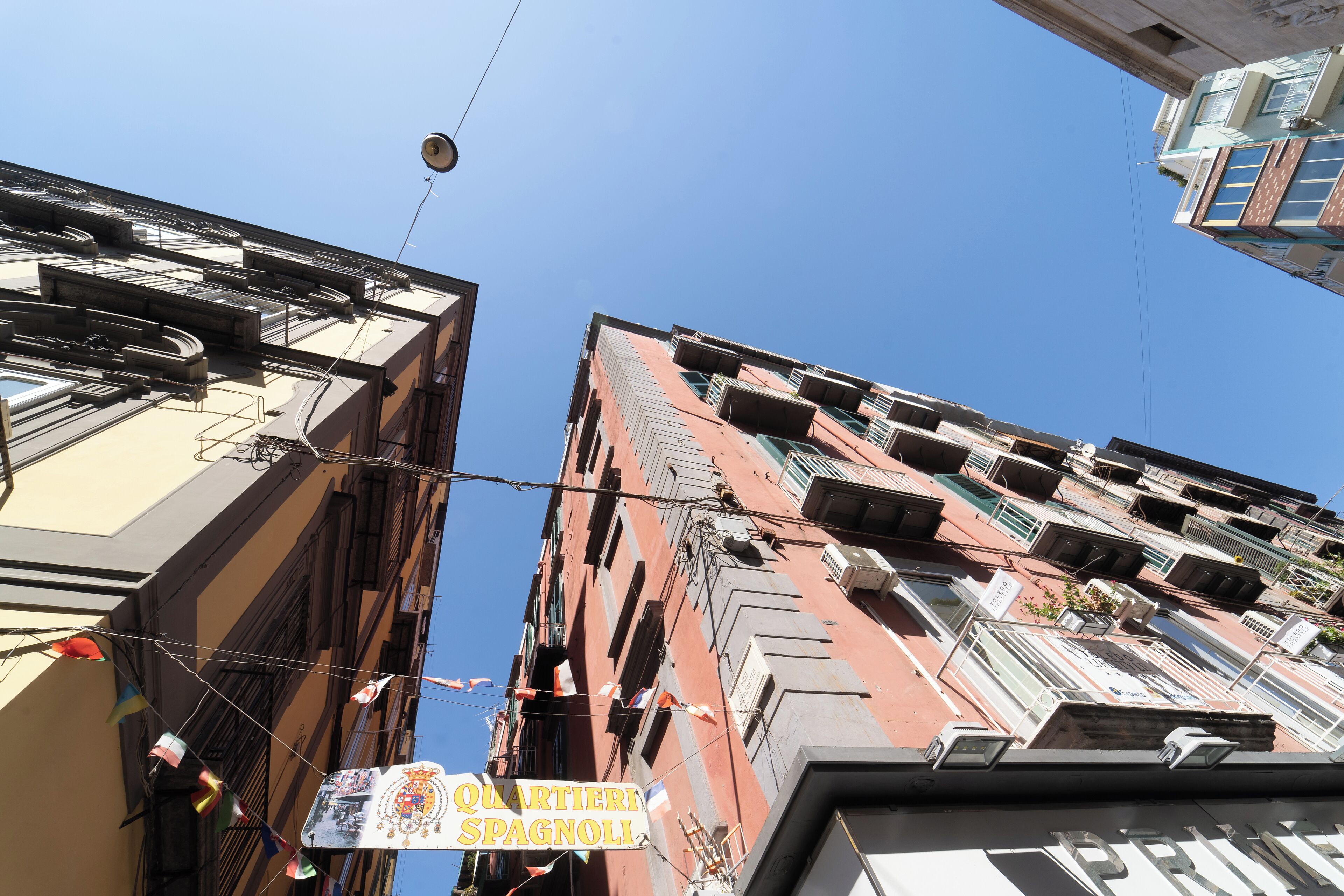 A view of a building with balconies and a sign reading "QUARTIER SPAGNOLI".