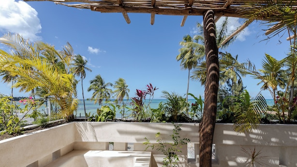 Una terrazza con vista sul mare, circondata da palme e piante in vaso.