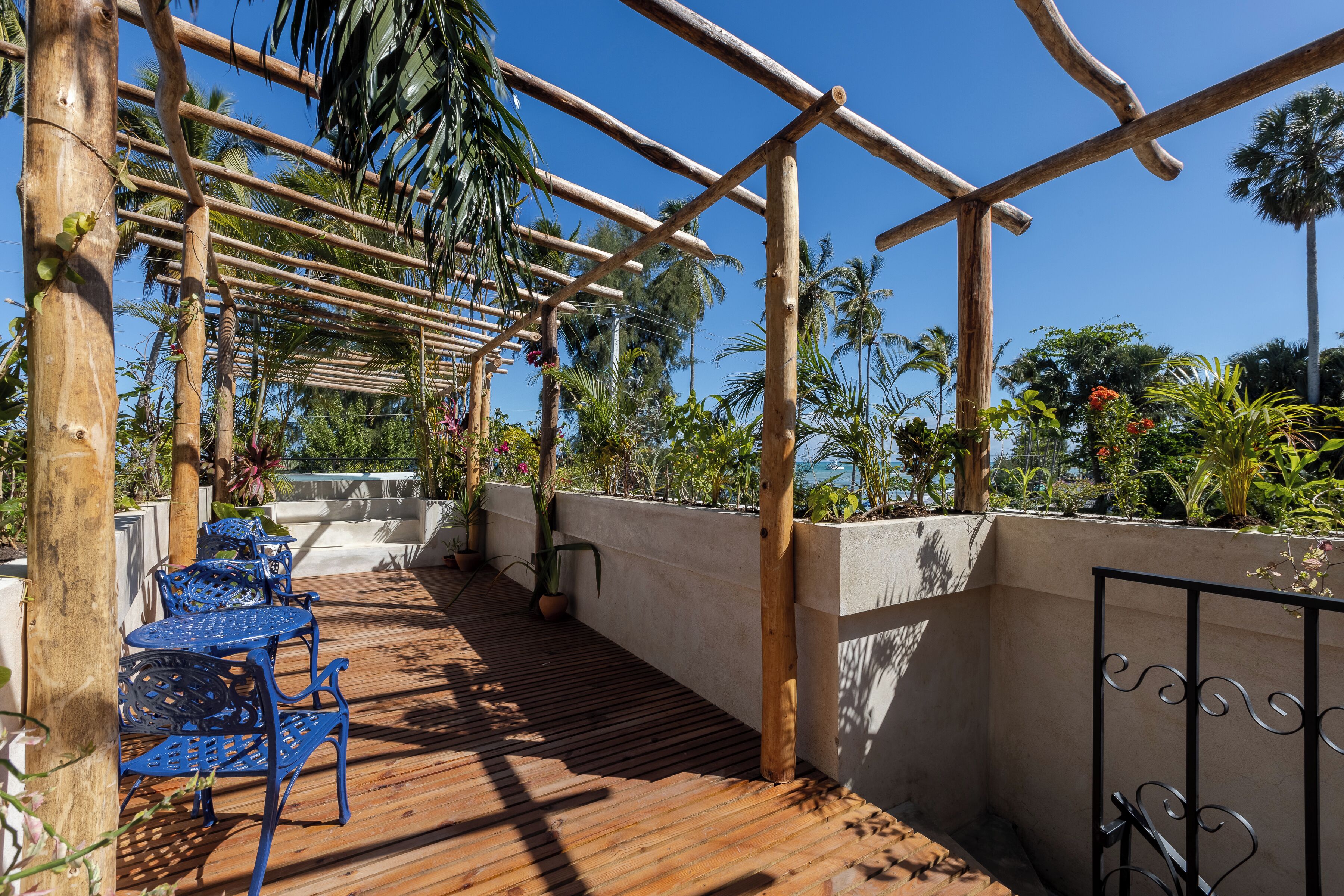 A wooden deck with blue metal chairs and a pergola structure.