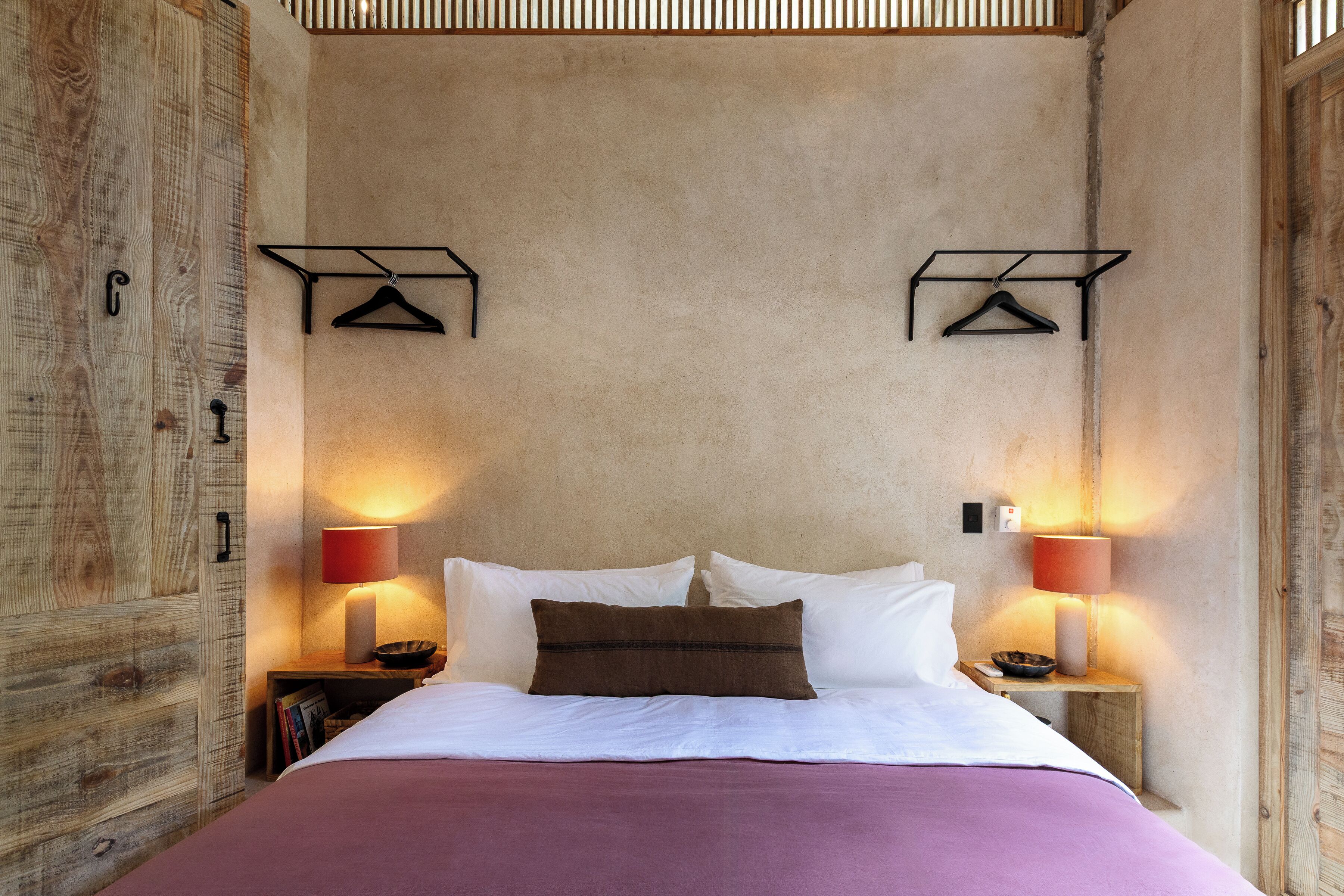 Un dormitorio con una cama grande, dos mesitas de noche con lámparas y paneles de madera en las paredes.