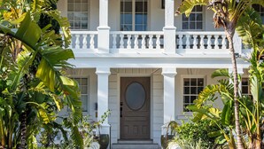 A two-story building with a white facade, a central entrance with a round door, and a balcony with white balustrades. - Hillcrest Boutique Hotel, Courtyard Villa Upper Pool View King -11 (St. George's)