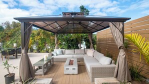 An outdoor patio with a covered seating area, a fire pit, and a dining table. - Hillcrest Boutique Hotel, Courtyard Villa Upper Pool View King -11 (St. George's)
