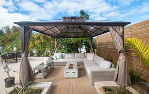 An outdoor patio with a covered seating area, a fire pit, and a dining table.