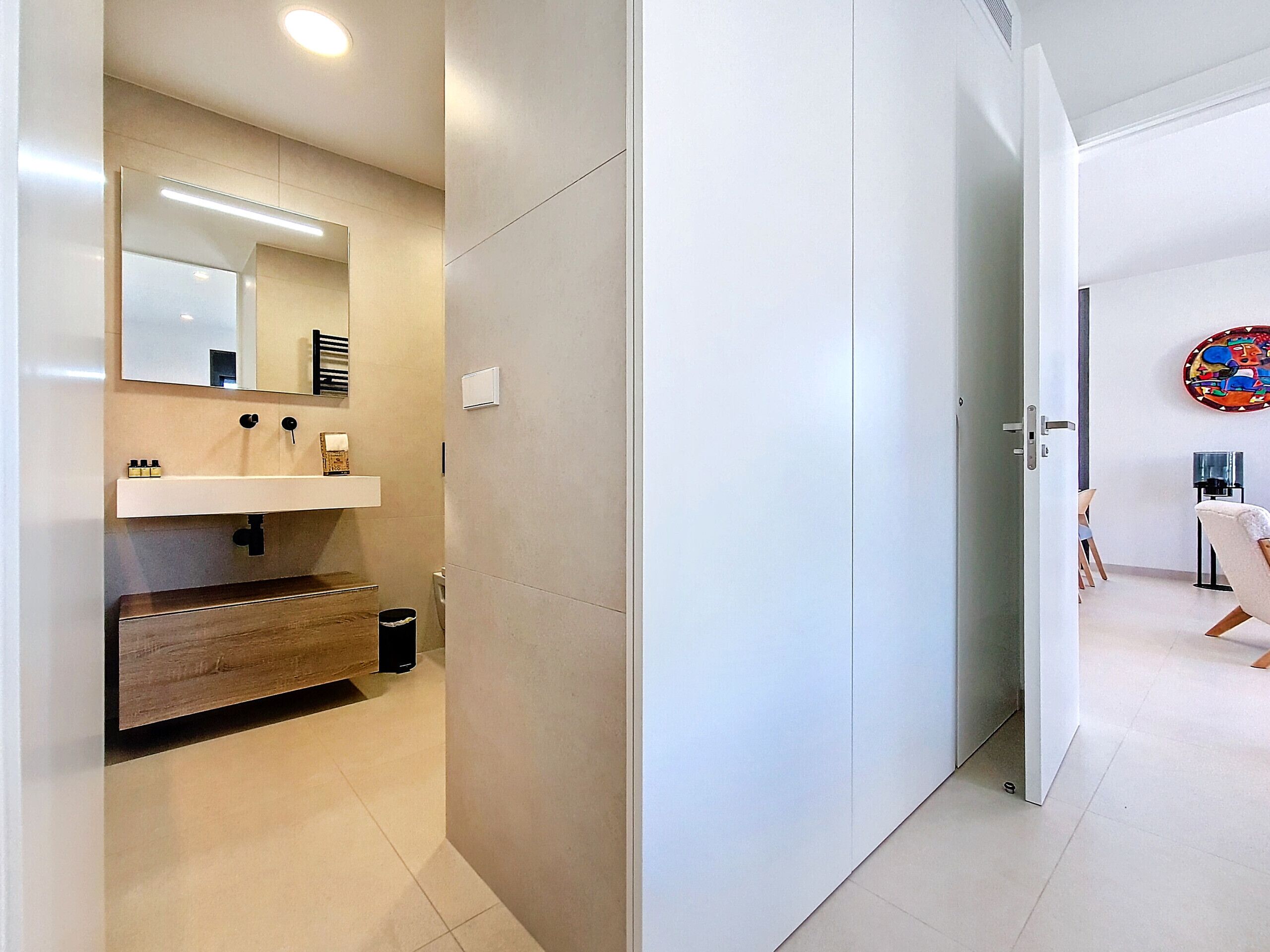 Ein modernes Badezimmer mit einem Holzkosmetikschrank, einem Spiegel und einer Toilette.