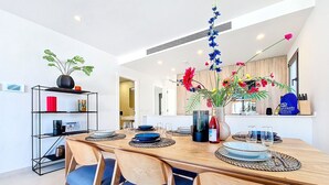 A modern dining area with a wooden table, blue chairs, and a vase of flowers. - Villa with private pool and Jacuzzi (San Javier)