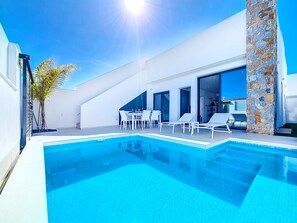 A modern outdoor swimming pool with lounge chairs and a dining area. - Villa with private pool and Jacuzzi (San Javier)