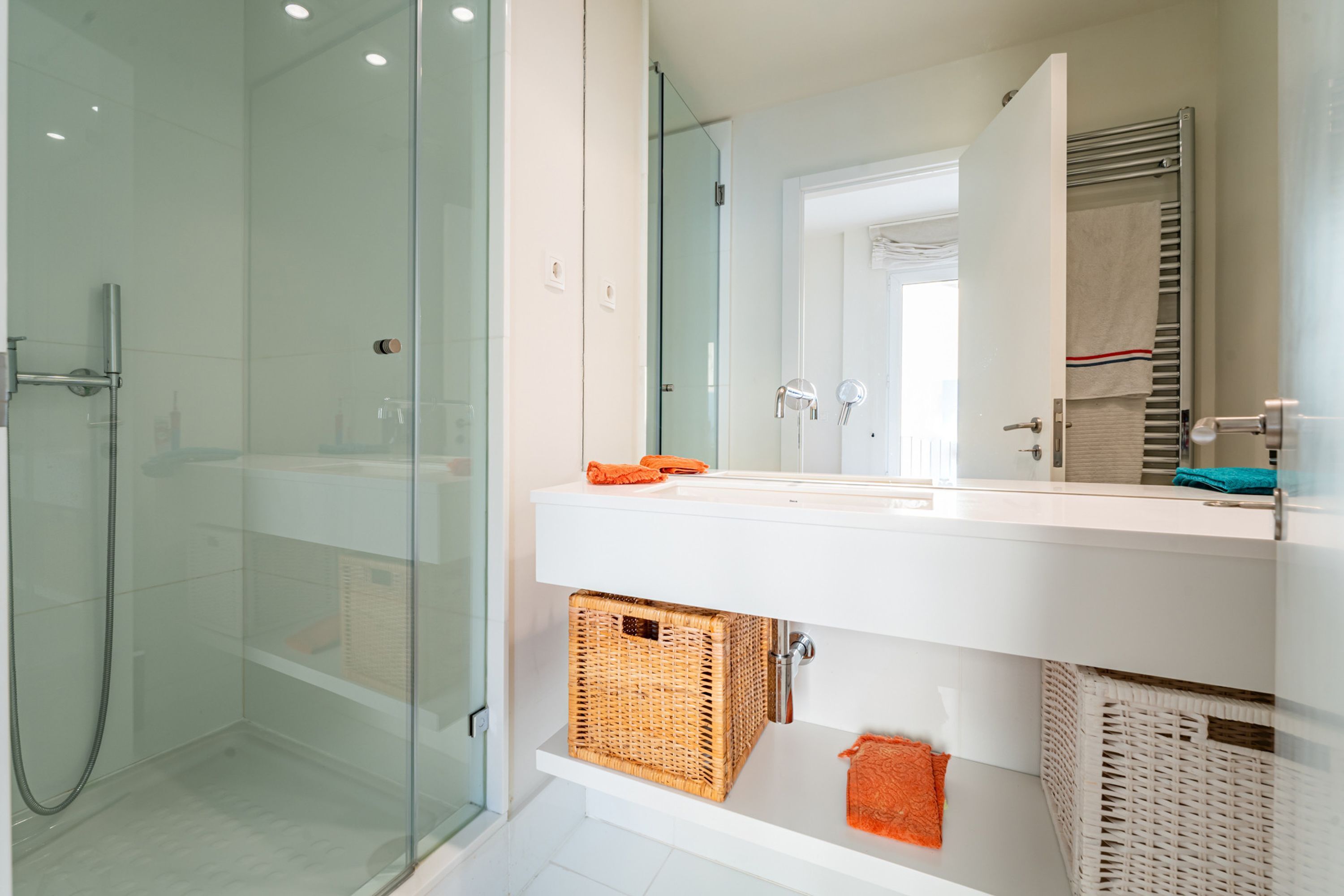 A modern bathroom with a glass shower enclosure, a white sink, and a large mirror.
