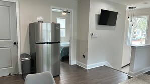 Una cocina moderna con un refrigerador de acero inoxidable, un comedor con mesa y sillas, y un televisor montado en la pared.