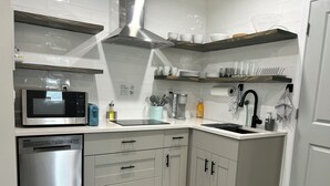 Una cocina moderna con armarios blancos, electrodomésticos de acero inoxidable y un microondas integrado.