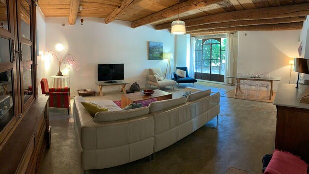 Ein gemütliches Wohnzimmer mit einer großen Couch, einem Fernseher und einem Essbereich mit Tisch und Stühlen.