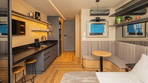 Eine moderne Küche mit Einbauofen, Kaffeemaschine und Spüle. Es gibt eine Sitzecke mit einer Bank und einem kleinen Tisch.