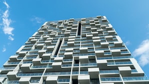 Ein hohes, modernes Gebäude mit einer markanten, geometrischen Fassade und zahlreichen Balkonen.