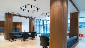 Ein modernes Interieur mit Holzvertäfelung, einem Fischgrätparkett und einer Sitzecke mit Sofas und Sesseln.