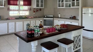 Une cuisine dotée d’un îlot central, de meubles blancs et d’un réfrigérateur.