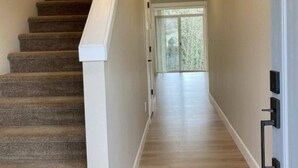 Un interior moderno con una escalera alfombrada que conduce a una habitación con un amplio ventanal.
