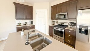 Una cocina moderna con armarios de madera oscura, electrodomésticos de acero inoxidable y una isla grande con un lavamanos.