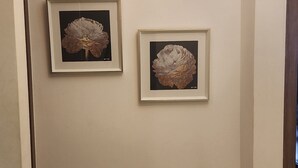 A hallway with two framed botanical prints on the wall, a dark wooden bench, and a modern chandelier. - 2-bedroom apartment in delightful Kingston with WiFi, fitness room, AC (Kingston)