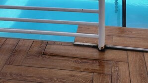 A pool with a metal safety railing, surrounded by a wooden deck. - 2-bedroom apartment in delightful Kingston with WiFi, fitness room, AC (Kingston)