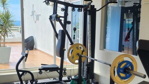 A gym with various exercise equipment, including a bench, weight bench, and a squat rack. - 2-bedroom apartment in delightful Kingston with WiFi, fitness room, AC (Kingston)