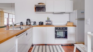 Ett modernt kök med vita skåp, en inbyggd ugn, en mikrovågsugn och en kaffebryggare.