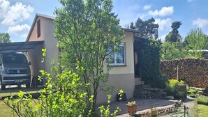 Une maison d’habitation avec un garage, un petit jardin et un abri de jardin.