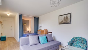 A modern living room with a grey sofa, a glass coffee table, and a patterned armchair. - Les Perlières: close to the beach, center (Arcachon)