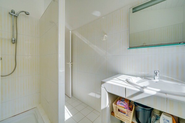 Une salle de bain moderne avec une douche, un lavabo et une étagère en verre.