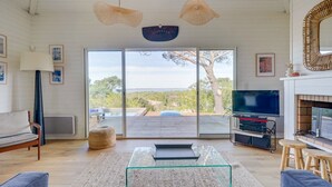 A spacious living room with a glass coffee table, a sofa, a TV, and a fireplace. - Villa Belvédère: pool, and beach 5 minutes- Pyla (La Teste-de-Buch)