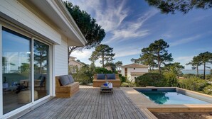 A wooden deck with outdoor furniture, a swimming pool, and a view of the sea. - Villa Belvédère: pool, and beach 5 minutes- Pyla (La Teste-de-Buch)