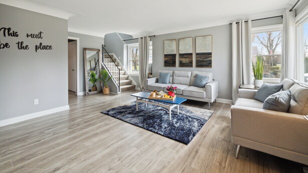 A modern living room with a staircase, a sofa, a coffee table, and artwork on the wall. - Spacious 7-bedroom house with WiFi and MASSIVE backyard in marvelous Plymouth (Plymouth)