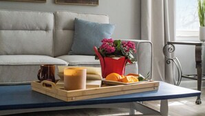 A modern living room with a sofa, a coffee table with a tray of orange slices, a candle, and a vase with flowers. - Spacious 7-bedroom house with WiFi and MASSIVE backyard in marvelous Plymouth (Plymouth)