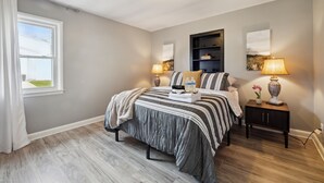 A bedroom with a bed, bedside tables, a window, and a wall-mounted shelf. - Spacious 7-bedroom house with WiFi and MASSIVE backyard in marvelous Plymouth (Plymouth)