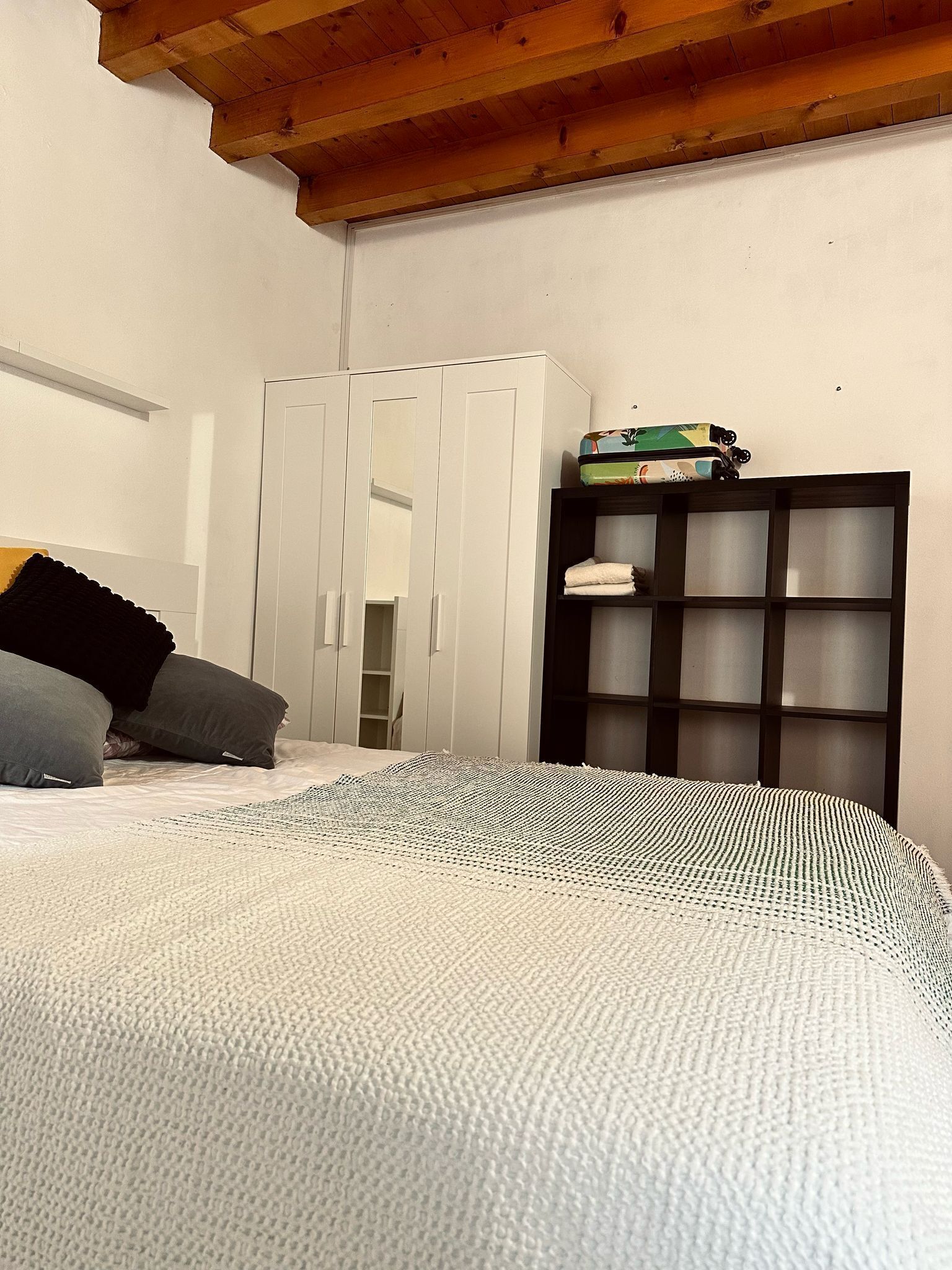 Une chambre à coucher avec un lit, une armoire et une étagère sur laquelle se trouve un jouet.
