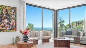 A modern living room with a large painting, a round wooden coffee table, and a sofa. - Villa Sereno | Ref. #96 (Marbella)