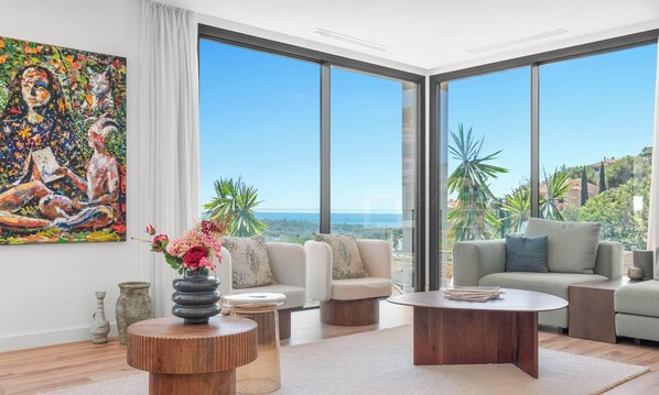 A modern living room with a large painting, a round wooden coffee table, and a sofa. - Villa Sereno | Ref. #96 (Marbella)