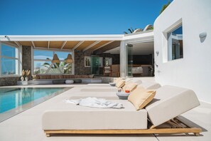 A modern poolside area with lounge chairs, a stone wall, and a clear view of the pool.