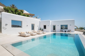 A modern pool area with white walls, a clear blue pool, and lounge chairs.